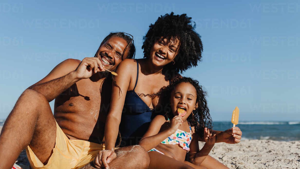Joyful family at beach on summer vacation eating ice cream.